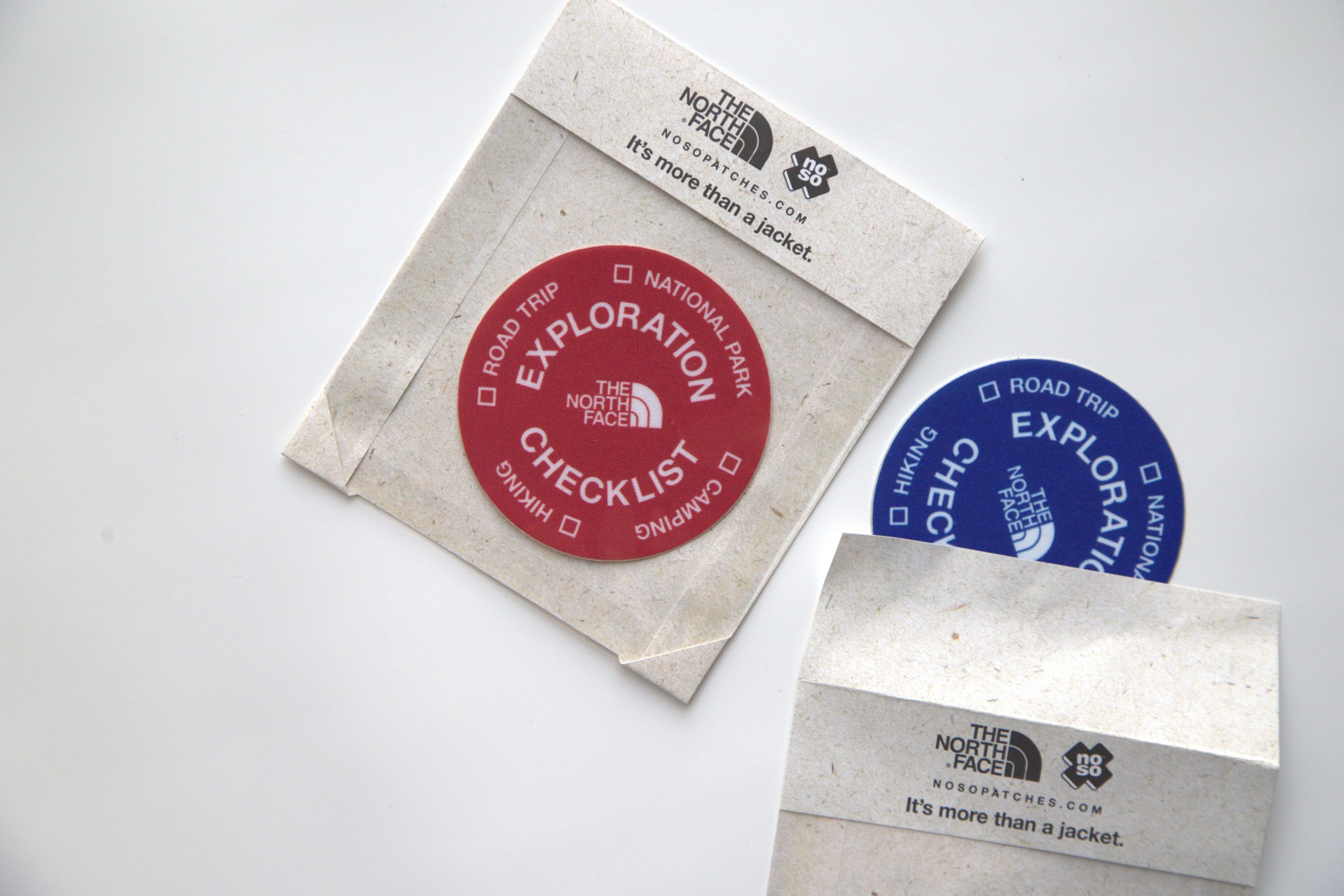Small windowed envelopes hold "Exploration Checklist" patches from The North Face.