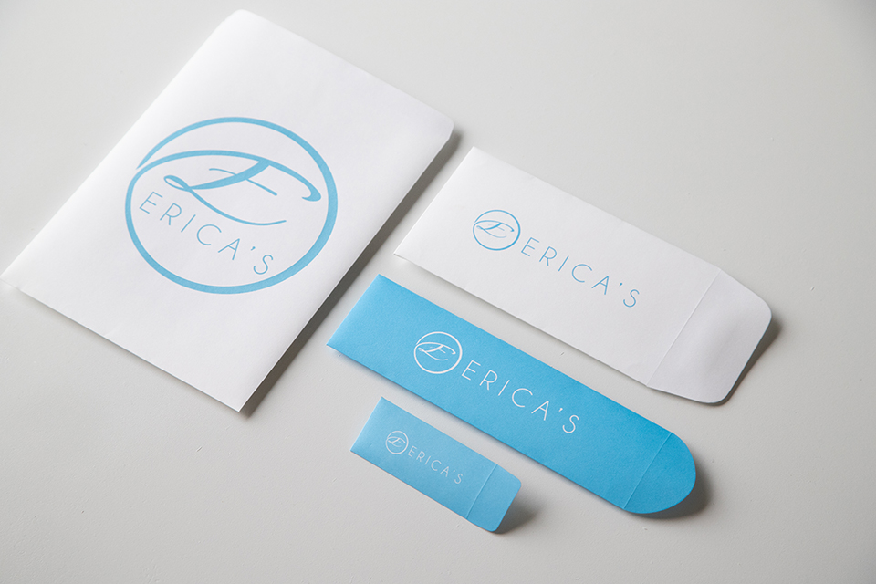 Four different sizes of Erica's ATA envelopes. Two are white with blue lettering, and two are blue with white terring.