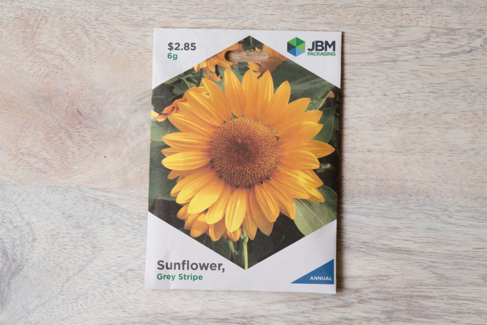 A seed packet with a picture of a sunflower and the JBM Packaging logo.