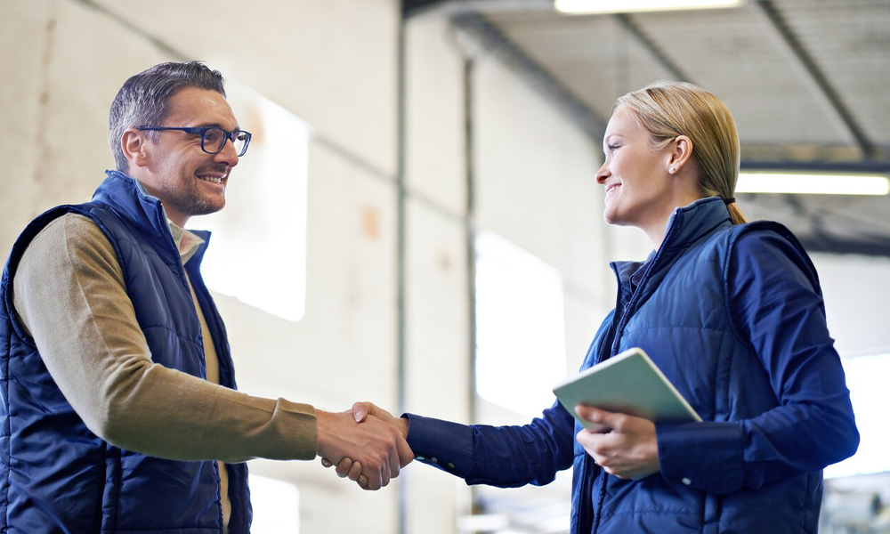 A man and woman smiling while shaking hands.